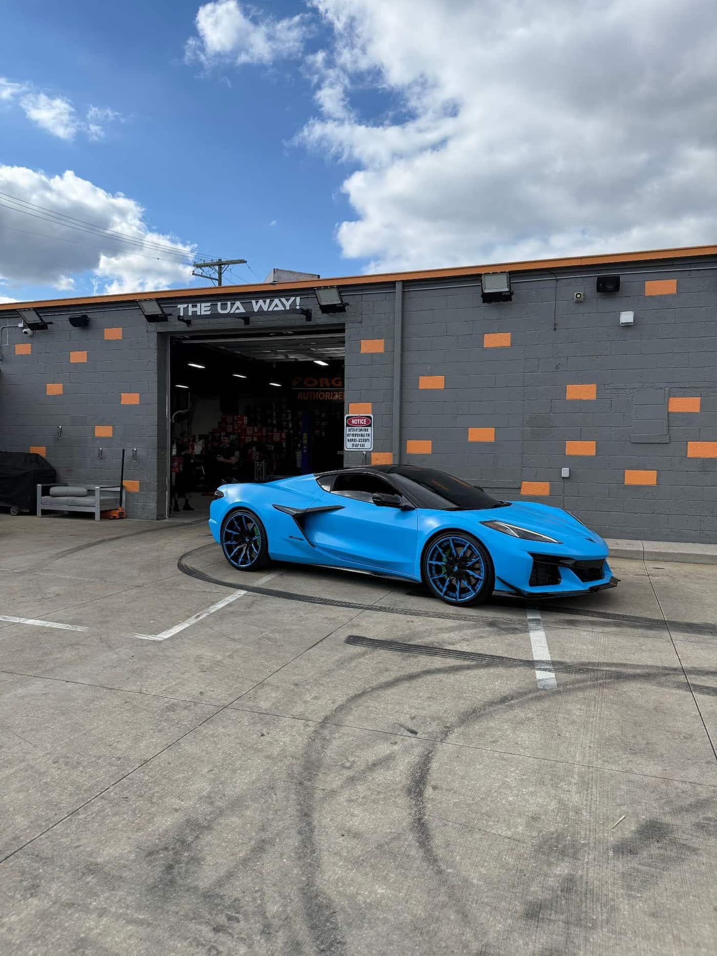 Side profile of a Corvette Z06 wrapped in Riptide Blue vinyl outside the Utica Auto Spa shop in Utica, MI