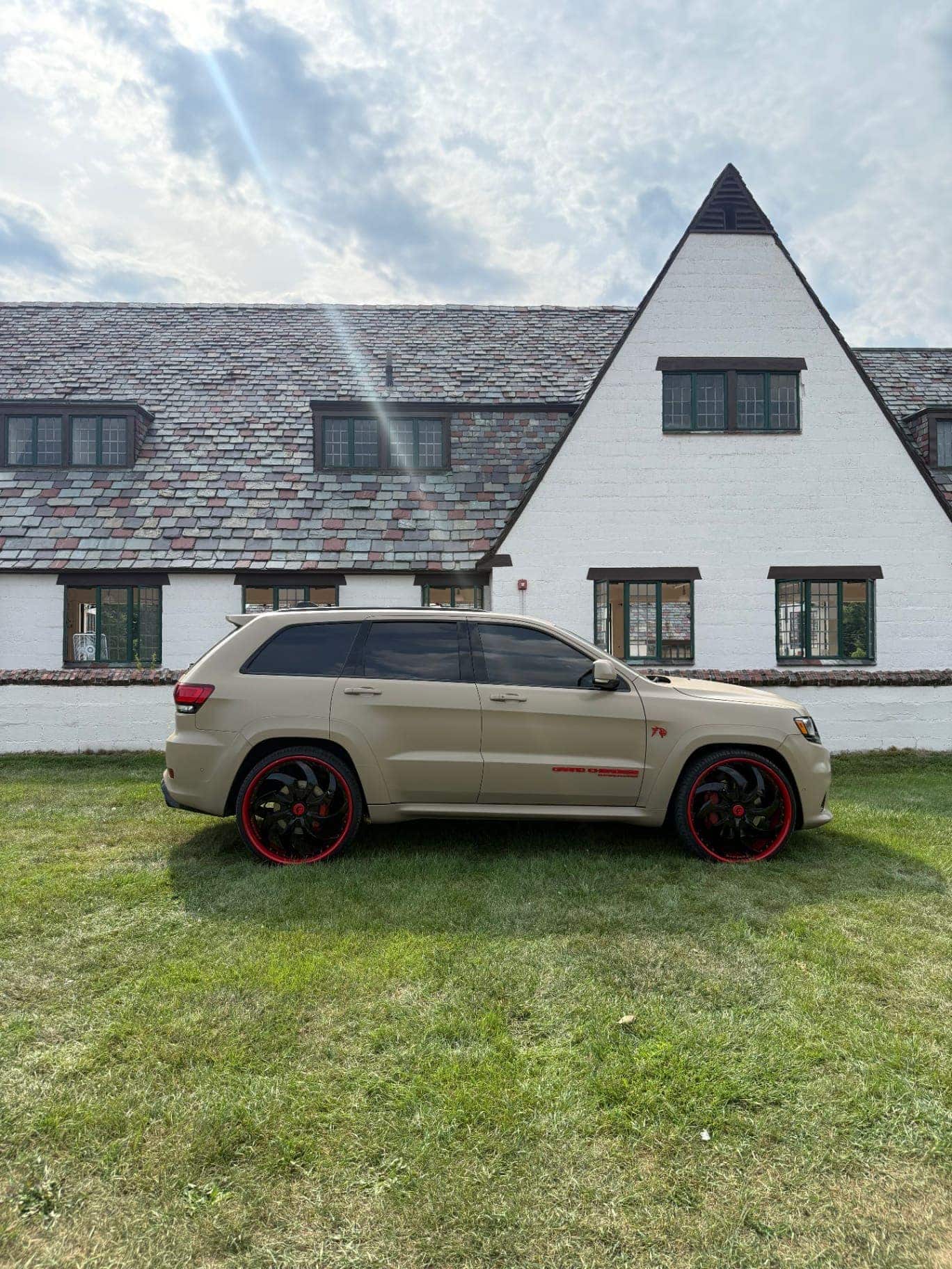 Side profile of a matte tan wrapped Jeep Grand Cherokee SRT on custom red and black Forgiato wheels