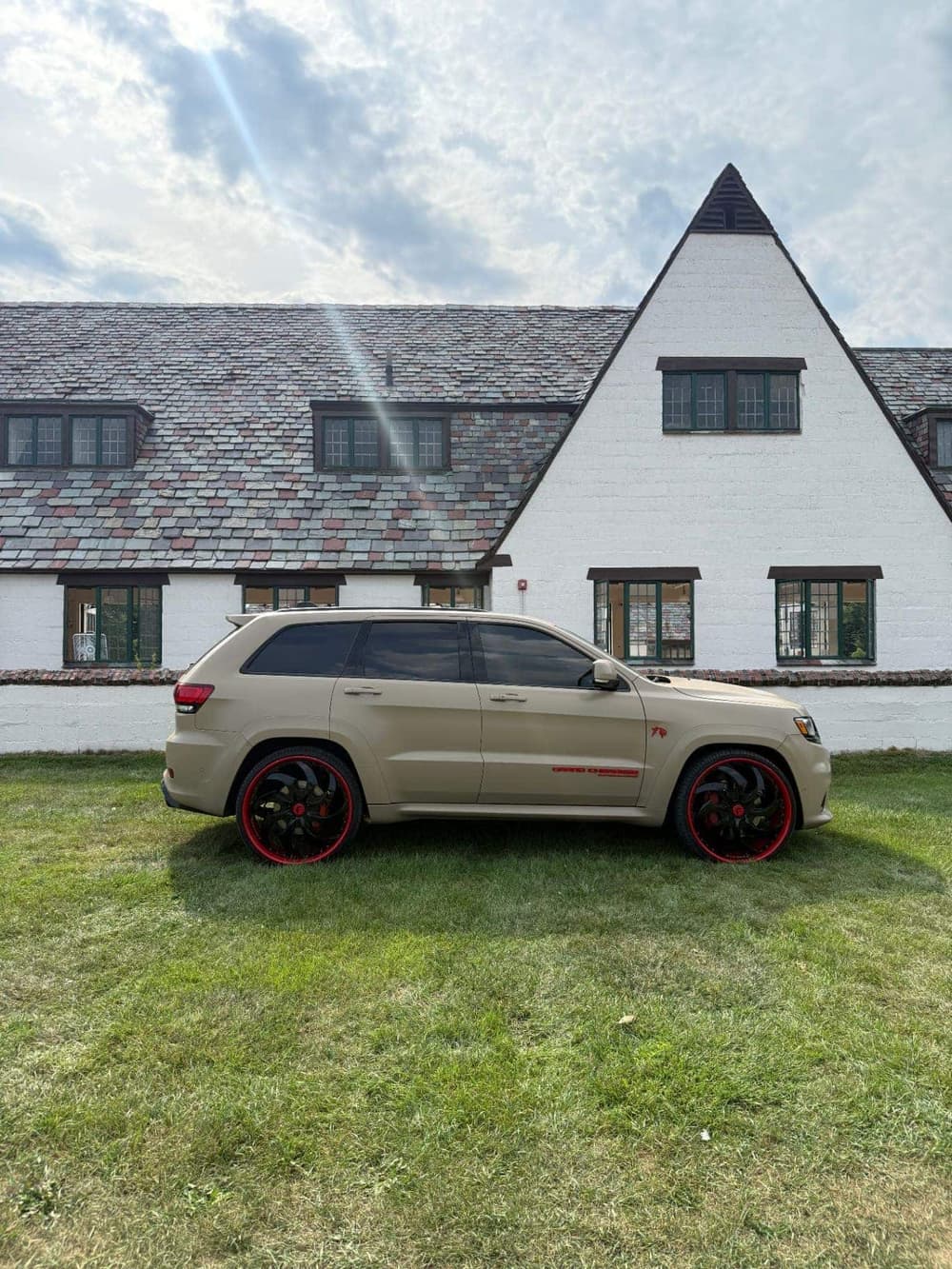 Side profile of a Jeep Grand Cherokee SRT wrapped in matte tan on custom red-lip Forgiato wheels