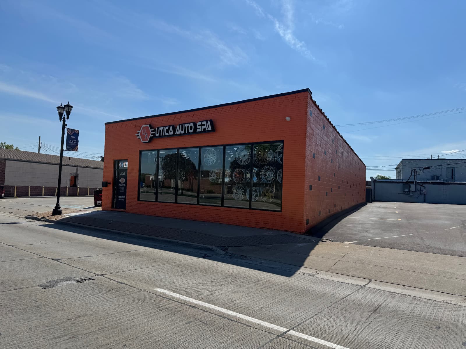 Angled exterior storefront photo of Utica Auto Spa with showroom windows and side lot